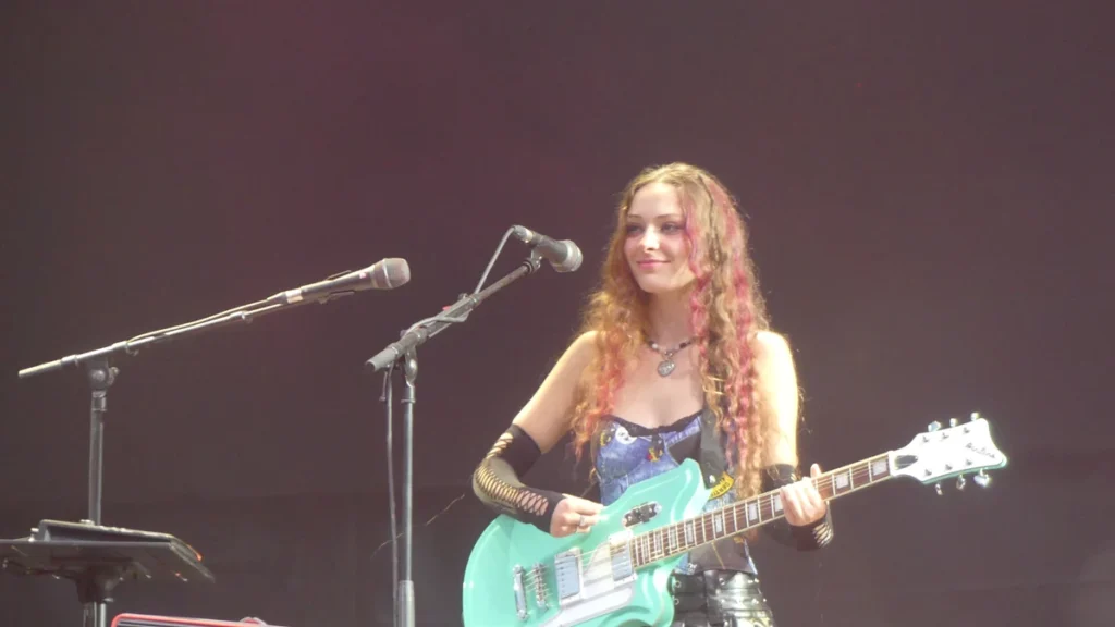 Holly Humberstone playing a mint green guitar on stage