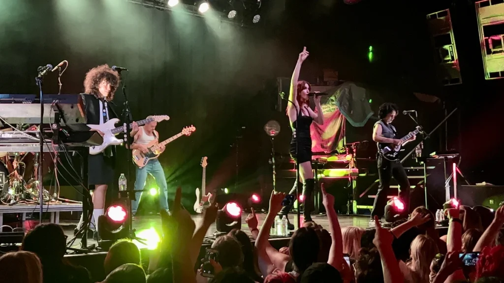 MUNA performing on stage with the crowd's hands raised