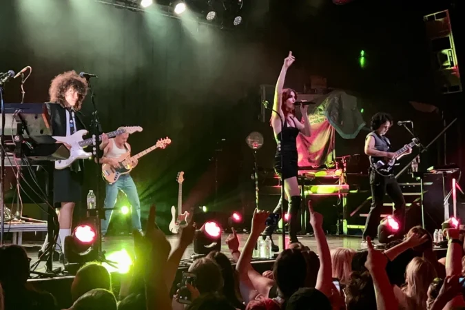 MUNA performing on stage with the crowd's hands raised