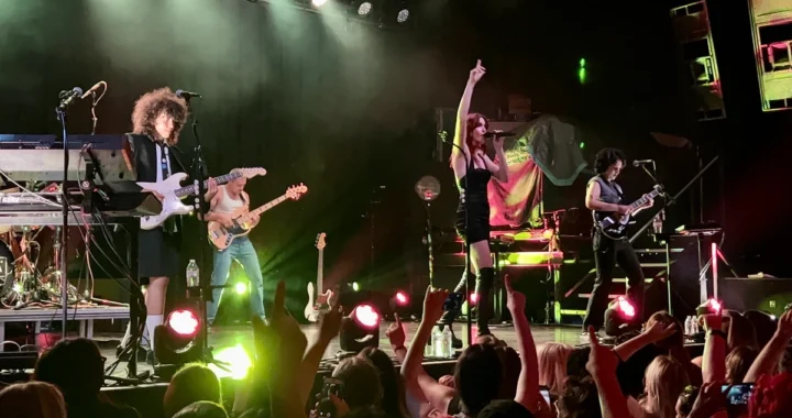 MUNA performing on stage with the crowd's hands raised