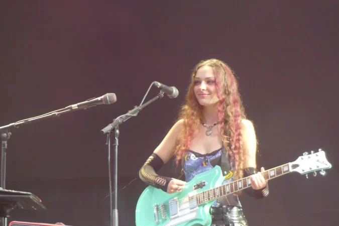 Holly Humberstone playing a mint green guitar on stage