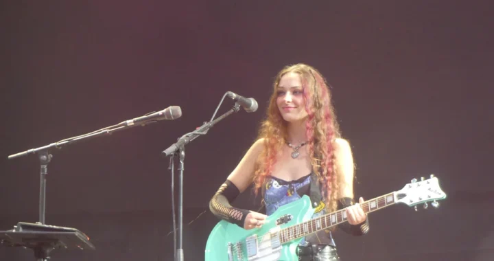 Holly Humberstone playing a mint green guitar on stage