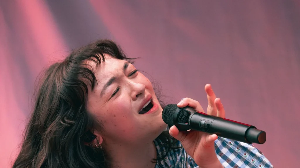 mxmtoon singing into a microphone on stage