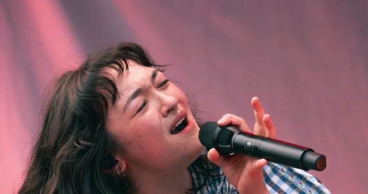 mxmtoon singing into a microphone on stage