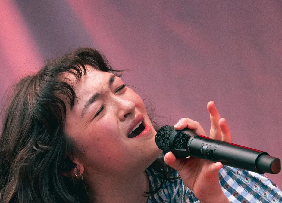 mxmtoon singing into a microphone on stage