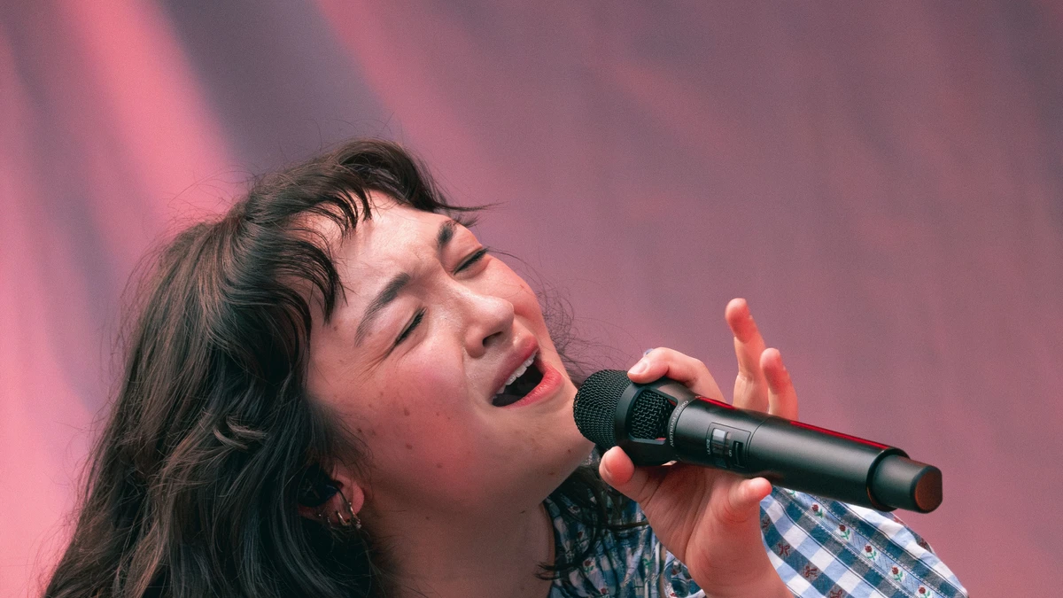 mxmtoon singing into a microphone on stage