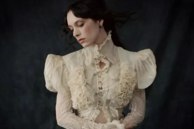 Holly Humberstone in a cream ruffled blouse against a dark backdrop