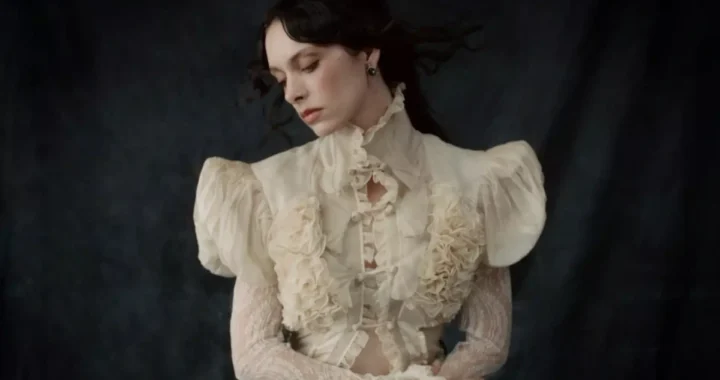 Holly Humberstone in a cream ruffled blouse against a dark backdrop