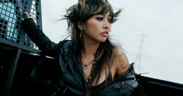 Beabadoobee in a Pylon-era press photo with an electricity pylon behind her
